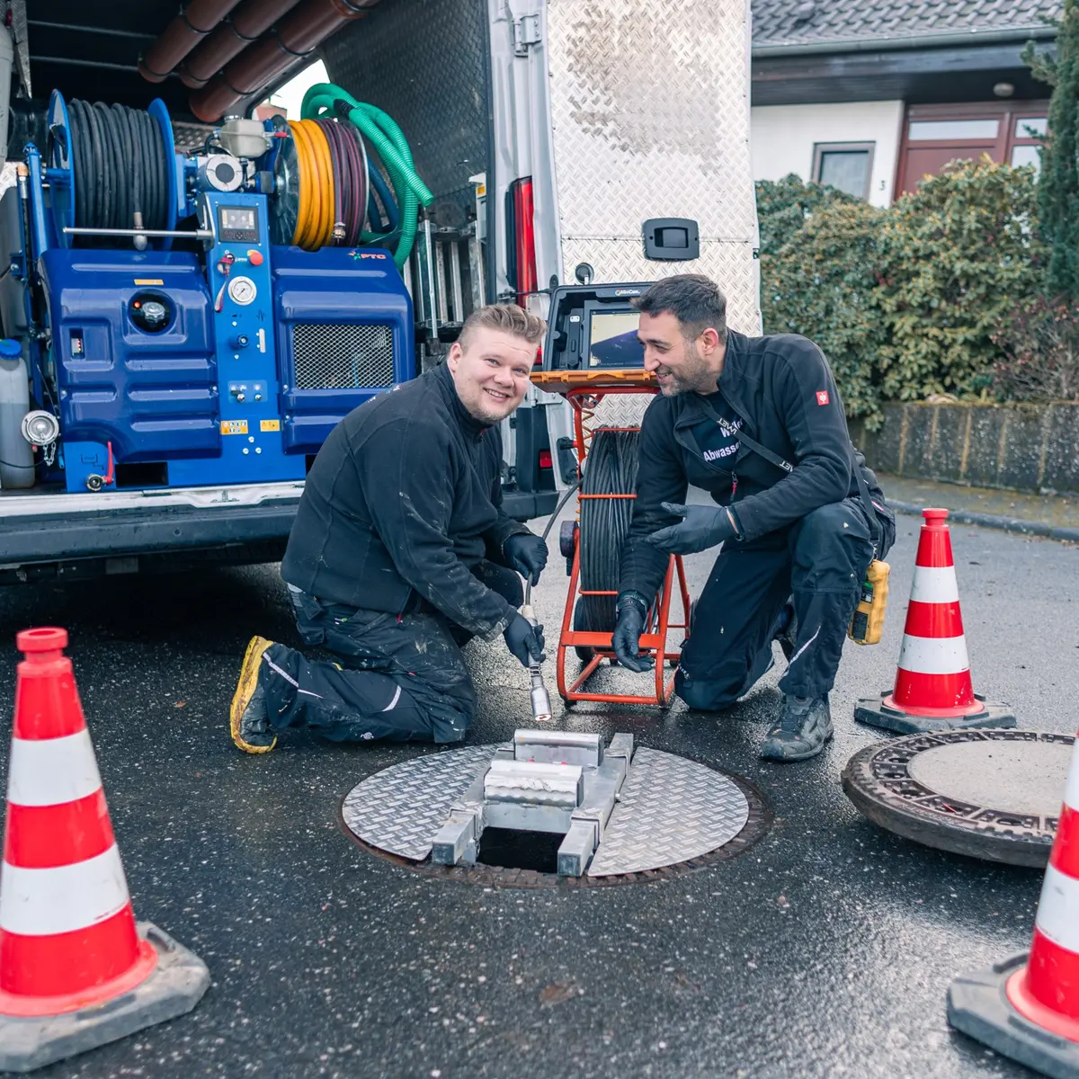Zwei Techniker von Weller Abwassertechnik arbeiten an einem geöffneten Kanalschacht