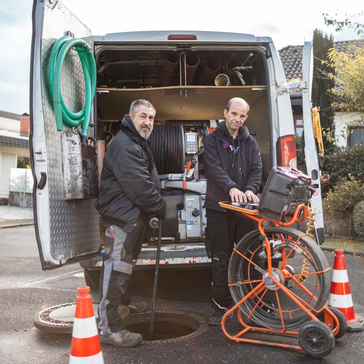 Zwei Techniker mit Kamerawagen an einem geöffneten Schacht