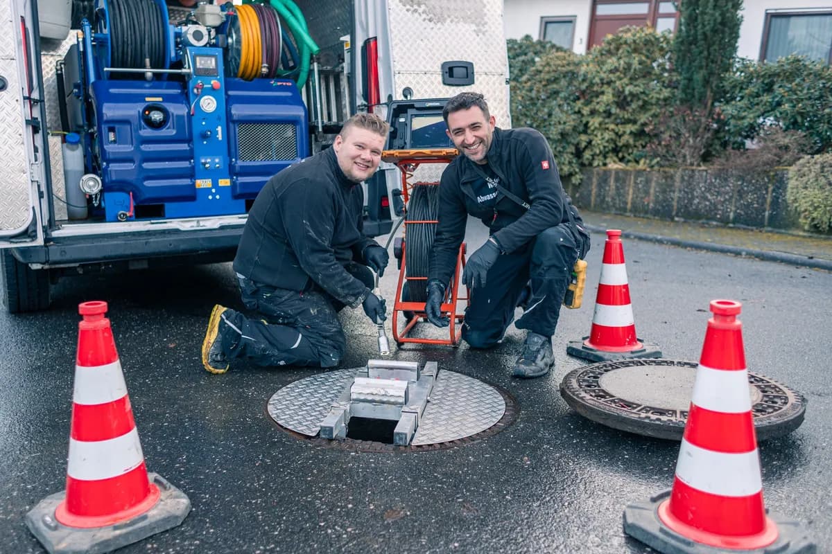 Zwei Techniker arbeiten am geöffneten Kanalschacht